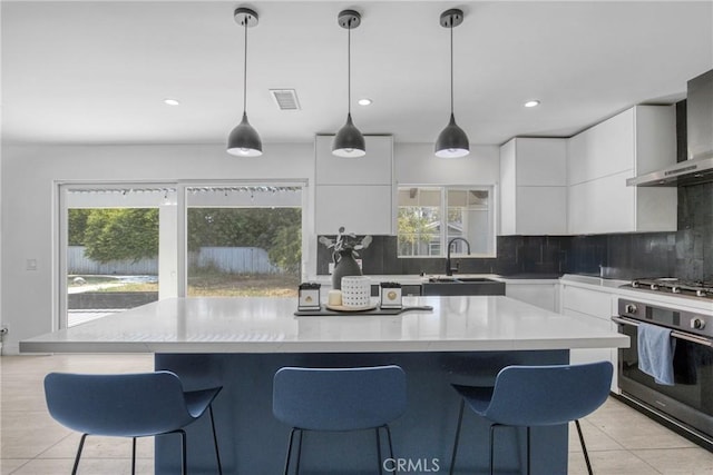 8140 Quartz Ave, Winnetka, CA 91306 - kitchen featuring appliances with stainless steel finishes, wall chimney range hood, modern cabinets, backsplash, and a kitchen breakfast bar