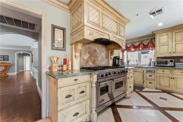 34037 Agua Dulce Canyon Rd, Agua Dulce, CA 91390 - kitchen with range with two ovens, cream cabinetry, arched walkways, ornamental molding, and decorative backsplash