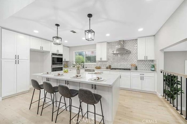 6212 Sacramento Ave, Rancho Cucamonga, CA 91701 - kitchen with wall chimney range hood, stainless steel double oven, white cabinetry, backsplash, and light wood-style floors