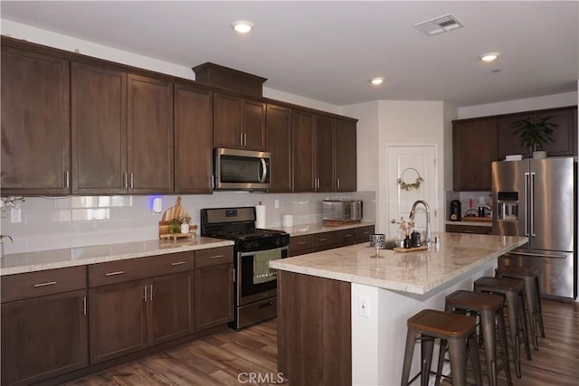 27082 Nolana Way, Menifee, CA 92584 - kitchen with appliances with stainless steel finishes, tasteful backsplash, a breakfast bar, and recessed lighting