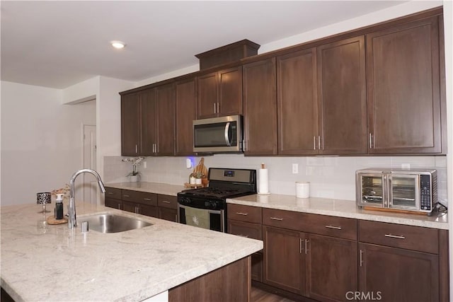 27082 Nolana Way, Menifee, CA 92584 - kitchen featuring stainless steel appliances, decorative backsplash, light stone counters, and dark brown cabinets