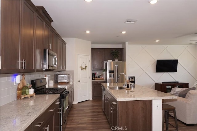 27082 Nolana Way, Menifee, CA 92584 - kitchen featuring appliances with stainless steel finishes, dark wood-style floors, light stone counters, a kitchen island with sink, and recessed lighting