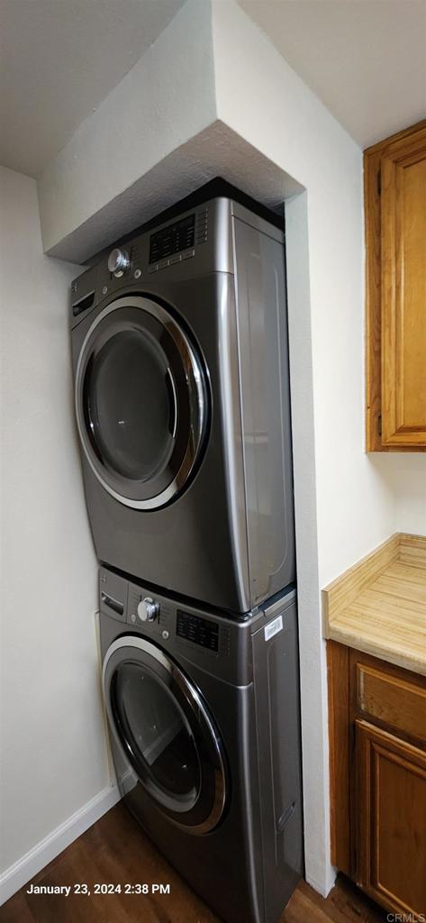 3040 Charwood Ct, Spring Valley, CA 91977 - laundry room with stacked washing machine and dryer, cabinet space, and dark wood-type flooring