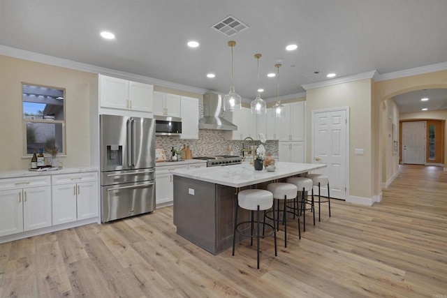 3017 Rue Montreux, Escondido, CA 92026 - kitchen featuring stainless steel appliances, wall chimney range hood, ornamental molding, arched walkways, and backsplash