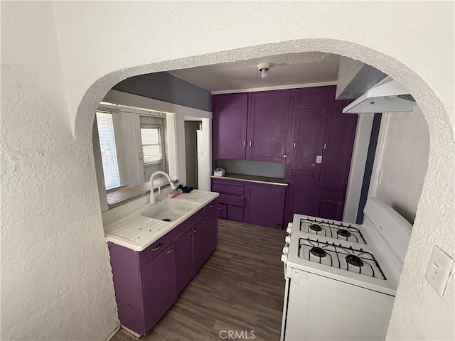 615 E 12th St, Pomona, CA 91766 - kitchen with a textured wall, white gas range oven, dark wood-style flooring, light countertops, and arched walkways