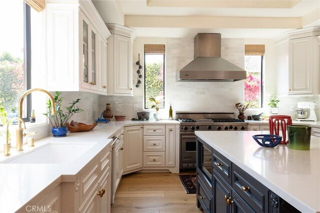 4620 Morse Ave, Sherman Oaks, CA 91423 - kitchen with wall chimney range hood, white cabinets, light countertops, and decorative backsplash