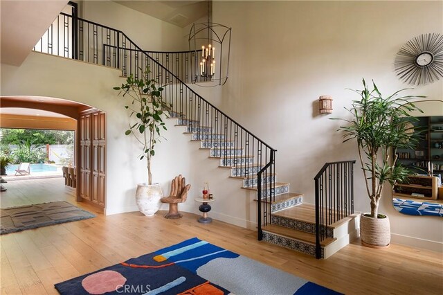 4620 Morse Ave, Sherman Oaks, CA 91423 - stairs featuring arched walkways, wood finished floors, a high ceiling, and a chandelier