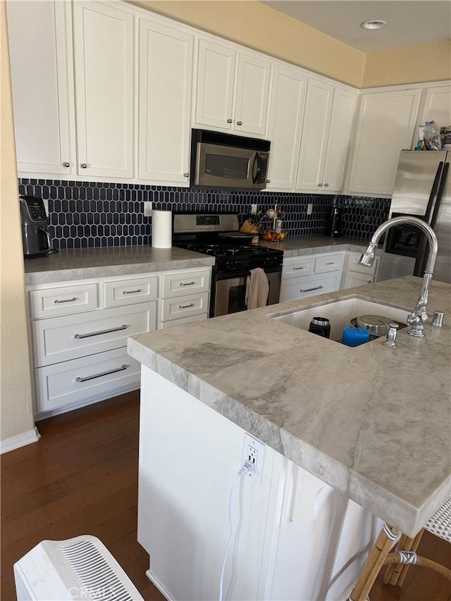 326 Borden Rd, San Marcos, CA 92069 - kitchen with appliances with stainless steel finishes, white cabinetry, tasteful backsplash, and dark wood-style flooring