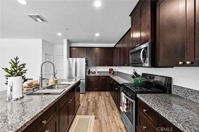 5609 Garibaldi Way, Fontana, CA 92336 - kitchen with stainless steel appliances, light stone counters, light wood-style flooring, dark brown cabinets, and recessed lighting