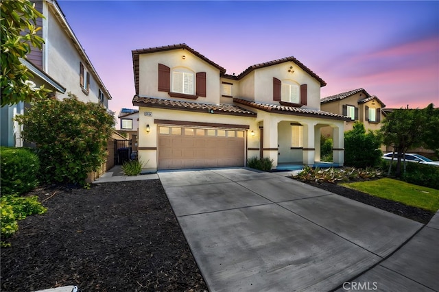 5609 Garibaldi Way, Fontana, CA 92336 - mediterranean / spanish-style house featuring stucco siding, driveway, a tiled roof, an attached garage, and a porch
