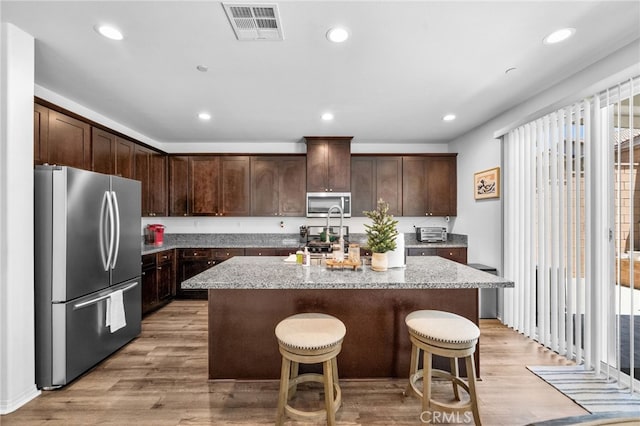 5609 Garibaldi Way, Fontana, CA 92336 - kitchen with stainless steel appliances, an island with sink, dark brown cabinetry, light stone countertops, and recessed lighting