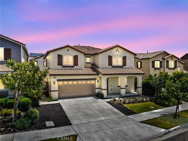 5609 Garibaldi Way, Fontana, CA 92336 - mediterranean / spanish house featuring a porch, a tiled roof, stucco siding, concrete driveway, and an attached garage