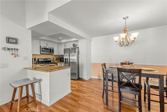 6210 Hartford Rd Unit 201, Yorba Linda, CA 92887 - kitchen with appliances with stainless steel finishes, a peninsula, a chandelier, dark stone countertops, and a raised ceiling