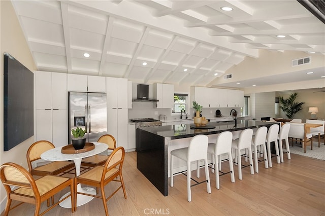 1700 Irvine Ave, Newport Beach, CA 92660 - kitchen featuring wall chimney exhaust hood, a kitchen breakfast bar, light wood finished floors, stainless steel fridge, and white cabinetry