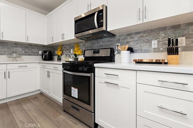 955 W Jasmine Way, Rialto, CA 92376 - kitchen with stainless steel appliances, light countertops, white cabinets, decorative backsplash, and light wood finished floors