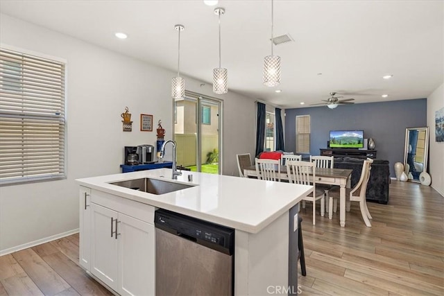 955 W Jasmine Way, Rialto, CA 92376 - kitchen featuring stainless steel dishwasher, light wood finished floors, a center island with sink, decorative light fixtures, and white cabinetry