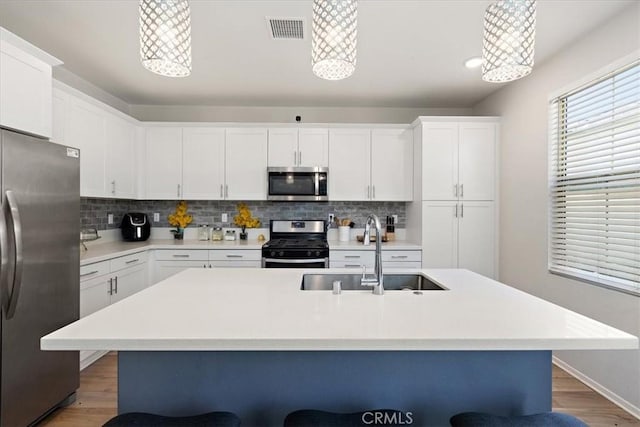 955 W Jasmine Way, Rialto, CA 92376 - kitchen with appliances with stainless steel finishes, tasteful backsplash, wood finished floors, and white cabinets