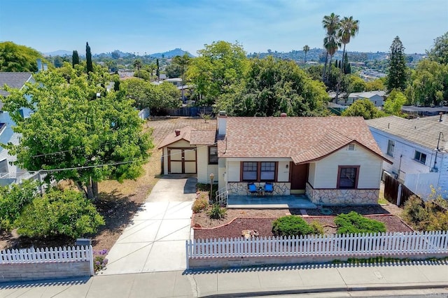 4693 71st St, La Mesa, CA 91942 - view of front of property with concrete driveway, a fenced front yard, a shingled roof, stone siding, and a porch
