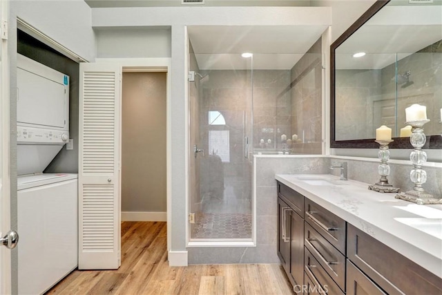 25072 Leucadia St Unit E, Laguna Niguel, CA 92677 - full bathroom with stacked washer / drying machine, double vanity, a shower stall, wood finished floors, and a closet