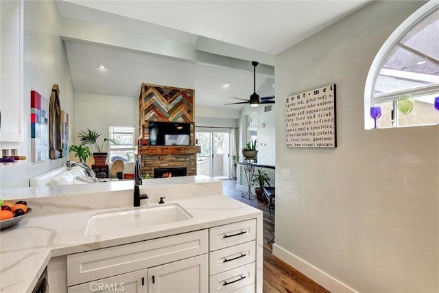 25072 Leucadia St Unit E, Laguna Niguel, CA 92677 - kitchen with a fireplace, open floor plan, wood finished floors, white cabinets, and light stone counters