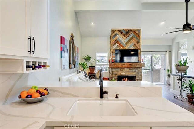 25072 Leucadia St Unit E, Laguna Niguel, CA 92677 - kitchen with open floor plan, ceiling fan, white cabinets, a fireplace, and light stone counters