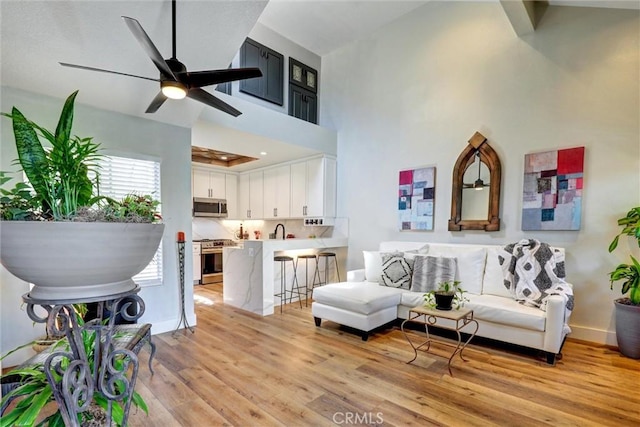 25072 Leucadia St Unit E, Laguna Niguel, CA 92677 - living room featuring light wood-style flooring, ceiling fan, and a towering ceiling