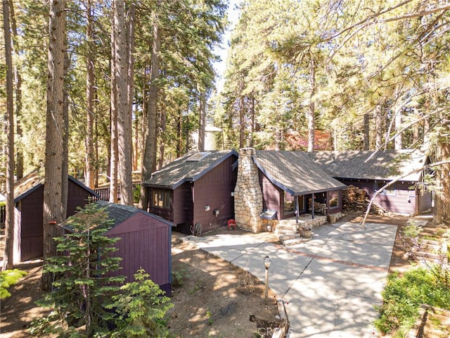 31701 Christmas Tree Ln, Running Springs, CA 92382 - view of front of home featuring a storage shed, a chimney, and a shingled roof
