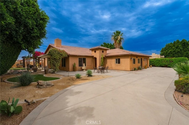 79140 Fred Waring Dr, Bermuda Dunes, CA 92203 - mediterranean / spanish house featuring stucco siding, a tiled roof, a chimney, and a patio