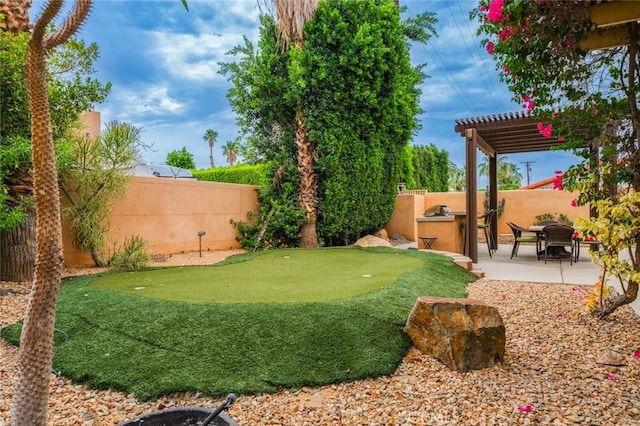 79140 Fred Waring Dr, Bermuda Dunes, CA 92203 - fenced backyard with a pergola, a putting area, a patio, and an outdoor kitchen