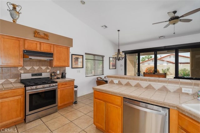 79140 Fred Waring Dr, Bermuda Dunes, CA 92203 - kitchen featuring stainless steel appliances, under cabinet range hood, backsplash, light tile patterned flooring, and a chandelier