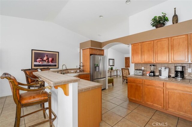 79140 Fred Waring Dr, Bermuda Dunes, CA 92203 - kitchen with stainless steel fridge with ice dispenser, tile counters, a peninsula, arched walkways, and vaulted ceiling