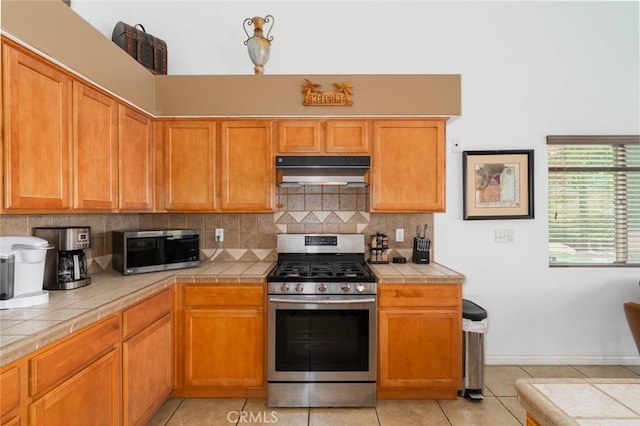 79140 Fred Waring Dr, Bermuda Dunes, CA 92203 - kitchen with stainless steel appliances, under cabinet range hood, tile countertops, backsplash, and light tile patterned floors