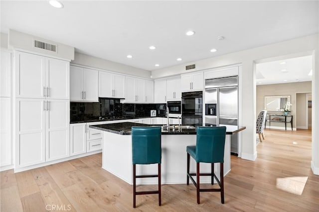 8 Pavona, Newport Coast, CA 92657 - kitchen with stainless steel built in fridge, a kitchen bar, white cabinets, decorative backsplash, and a kitchen island