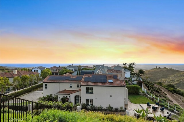 8 Pavona, Newport Coast, CA 92657 - back of house at dusk with stucco siding, solar panels, a tiled roof, and a fenced backyard