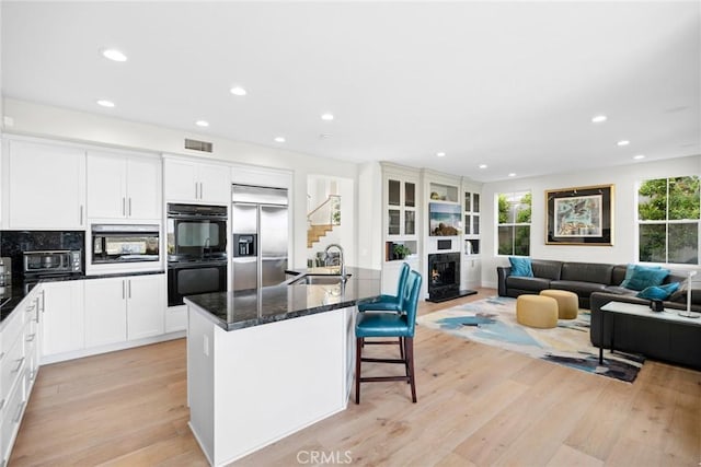 8 Pavona, Newport Coast, CA 92657 - kitchen featuring built in appliances, light wood finished floors, recessed lighting, a kitchen island with sink, and a breakfast bar area