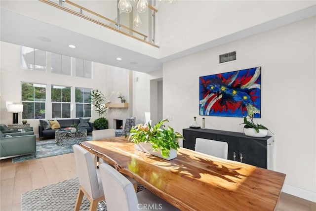 8 Pavona, Newport Coast, CA 92657 - dining area with a towering ceiling, wood finished floors, a large fireplace, a chandelier, and recessed lighting