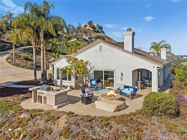 2240 Aqua Hill Rd, Fallbrook, CA 92028 - back of property featuring a chimney, exterior kitchen, a patio, stucco siding, and an outdoor living space with a fire pit