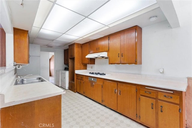 1305 S Westchester Dr, Anaheim, CA 92804 - kitchen with washer and dryer, under cabinet range hood, white gas cooktop, brown cabinets, and light flooring