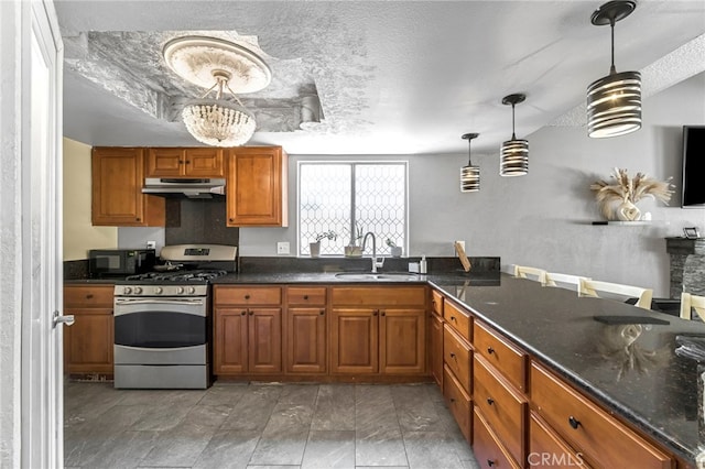4883 E Geary St, Fresno, CA 93725 - kitchen featuring gas stove, under cabinet range hood, brown cabinetry, hanging light fixtures, and a textured ceiling