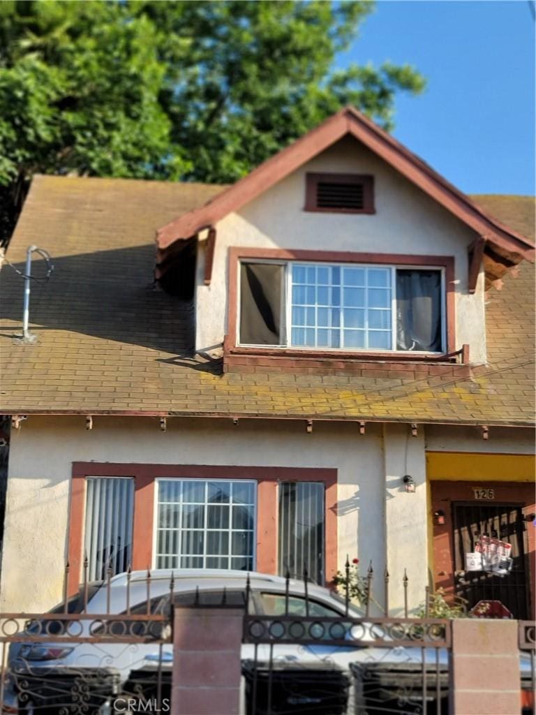 126 W 54th St, Los Angeles, CA 90037 - view of front of home with stucco siding, roof with shingles, and a fenced front yard