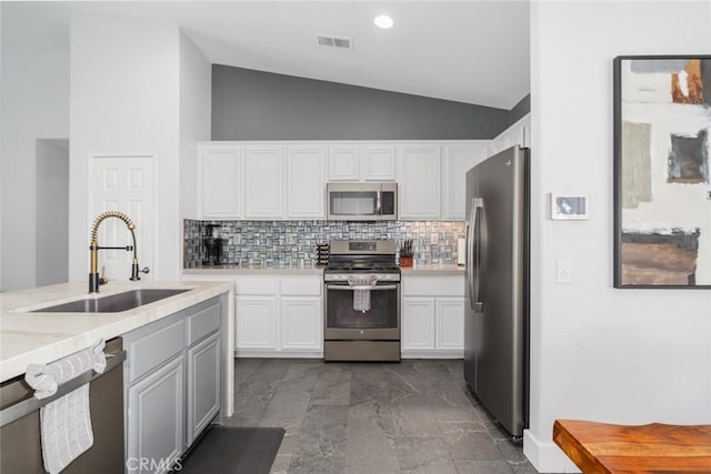 47645 Calle Diamante, Indio, CA 92201 - kitchen with appliances with stainless steel finishes, vaulted ceiling, backsplash, light countertops, and white cabinetry