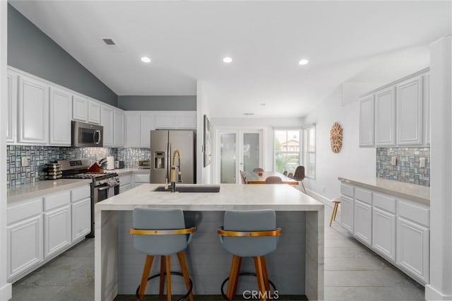 47645 Calle Diamante, Indio, CA 92201 - kitchen with stainless steel appliances, tasteful backsplash, a kitchen breakfast bar, white cabinetry, and recessed lighting