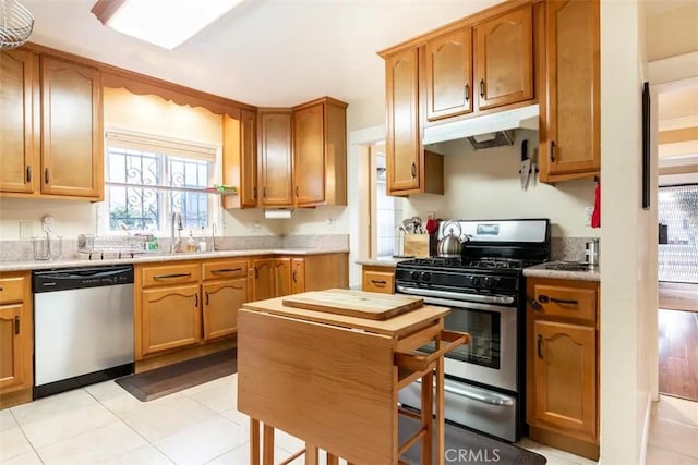 5162 S Manhattan Pl, Los Angeles, CA 90062 - kitchen featuring appliances with stainless steel finishes, under cabinet range hood, light countertops, and brown cabinetry