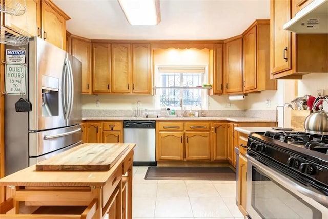 5162 S Manhattan Pl, Los Angeles, CA 90062 - kitchen with appliances with stainless steel finishes, under cabinet range hood, butcher block countertops, and light tile patterned flooring