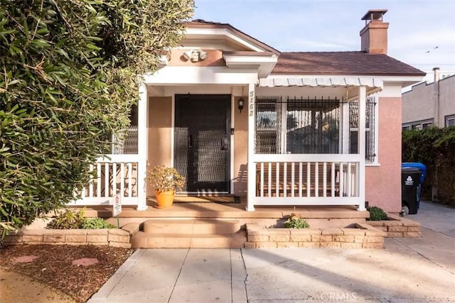 5162 S Manhattan Pl, Los Angeles, CA 90062 - property entrance with stucco siding, a chimney, and a porch