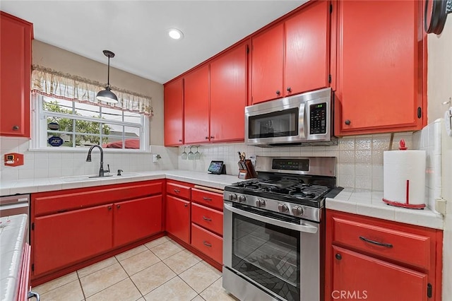 4303 E De Ora Way, Long Beach, CA 90815 - kitchen featuring stainless steel appliances, red cabinetry, light tile patterned floors, tasteful backsplash, and tile countertops