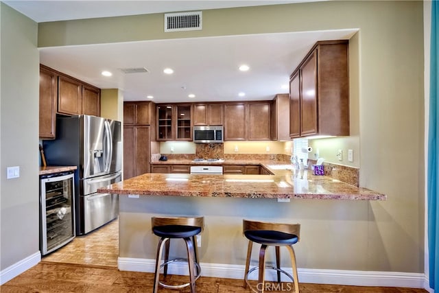 66 Glenalmond Ln, Ladera Ranch, CA 92694 - kitchen with wine cooler, stainless steel appliances, a peninsula, light stone counters, and glass insert cabinets