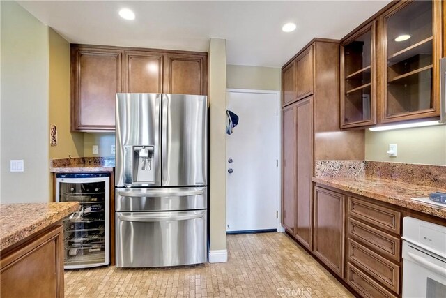 66 Glenalmond Ln, Ladera Ranch, CA 92694 - kitchen with stainless steel fridge with ice dispenser, wine cooler, oven, glass insert cabinets, and light stone countertops