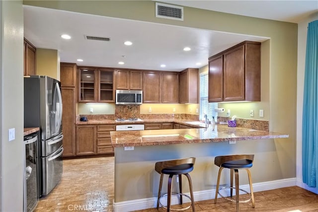66 Glenalmond Ln, Ladera Ranch, CA 92694 - kitchen with appliances with stainless steel finishes, a peninsula, a breakfast bar, brown cabinetry, and recessed lighting