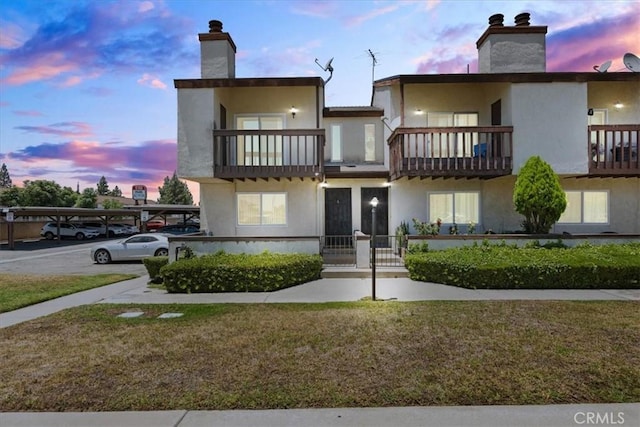 9100 Acacia Ave Unit 6, Fontana, CA 92335 - view of front of home with a balcony, covered parking, a chimney, and stucco siding